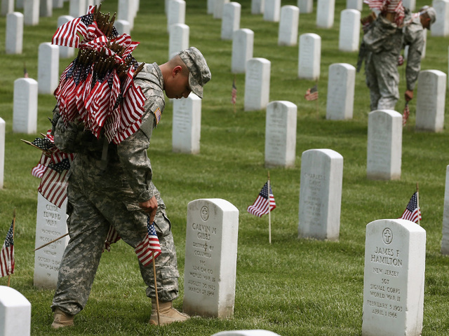Soldiers from the 3d U.S. Infantry Regiment (The Old Guard) place flags in front of the gravesites in Arlington National Cemetary, Va., May 22, 2014, during "Flags In".  U.S. Army photo by Klinton Smith.